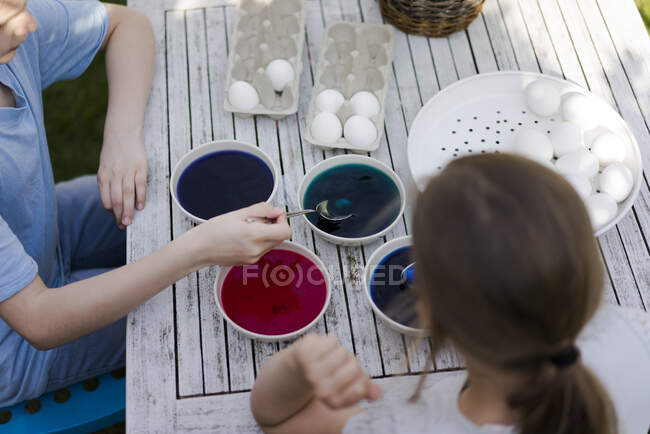 Дві дівчинки фарбують великодні яйця на городі. — стокове фото