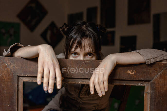 Portrait d'une peintre féminine dans son atelier appuyé sur un cadre photo — Photo de stock