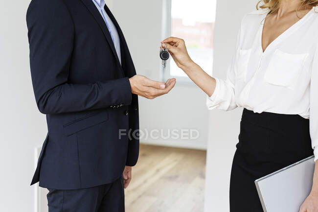 Close-up of real estate agent handing over key to client in new home — Stock Photo