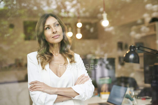 Mujer de negocios con brazos cruzados detrás de la ventana - foto de stock