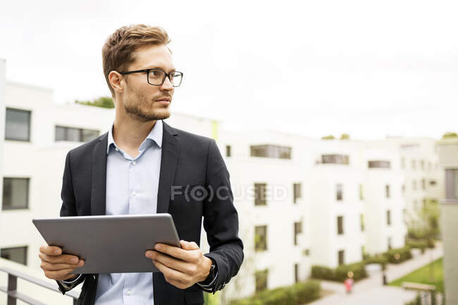 Geschäftsmann mit Tablet steht auf Balkon in Neubaugebiet — Stockfoto