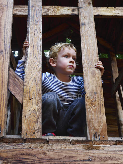 Retrato del niño agachado en el marco de escalada - foto de stock