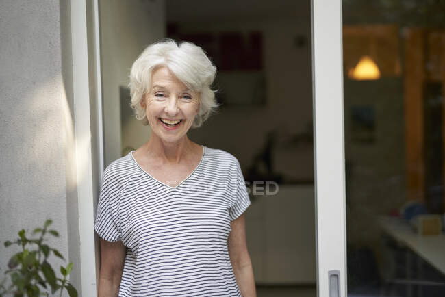 Портрет смішної зрілої жінки, що стоїть перед відкритими дверима тераси ввечері — стокове фото