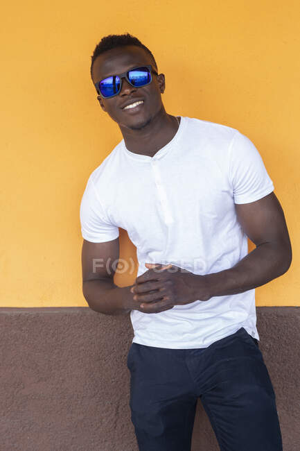 Retrato de un joven sonriente con camiseta blanca y gafas de sol - foto de stock