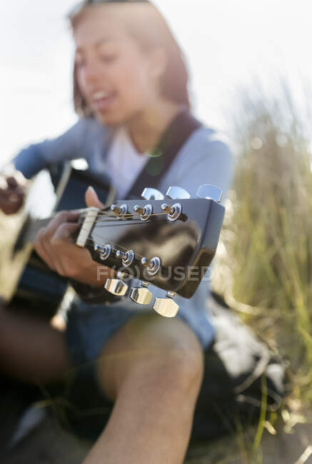 Close-up of young woman singing and playing guitar on the beach — Stock Photo