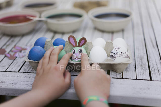Primer plano de la niña decorando huevo de Pascua en la mesa del jardín - foto de stock