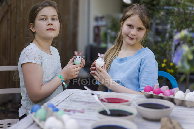 Porträt zweier Mädchen, die Ostereier auf dem Gartentisch verzieren — Stockfoto
