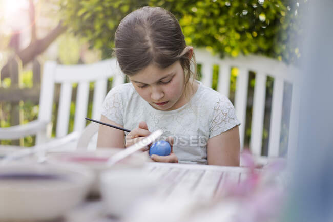 Дівчинка малює на городі яйце. — стокове фото