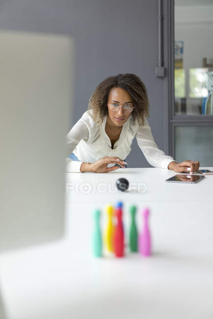 Joven freelancer jugando con alfileres en miniatura en el escritorio - foto de stock