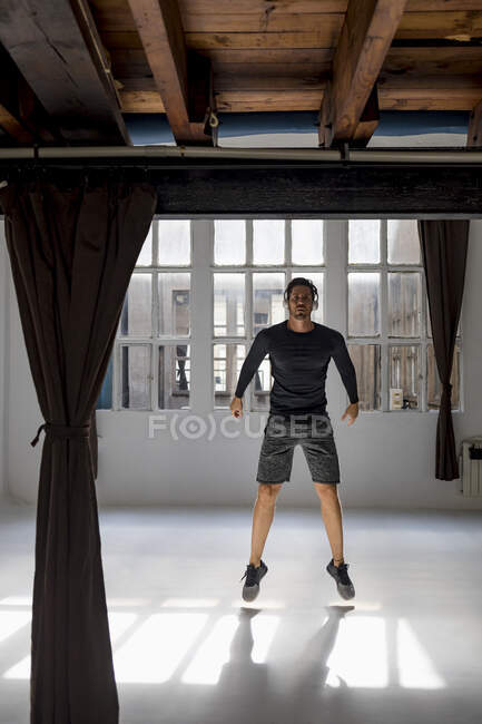 Atleta dinamico che salta in studio loft — Foto stock