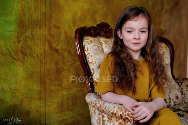 Retrato de una niña sentada en un sillón - foto de stock