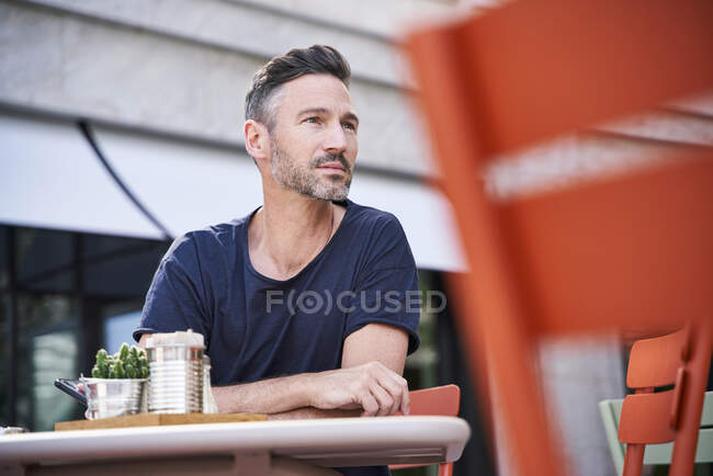 Lächelnd reifer Mann sitzt im Straßencafé — Stockfoto