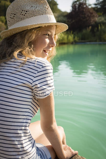 Girl with straw hat sitting at swimming pool, Tuscany, Italy — Stock Photo