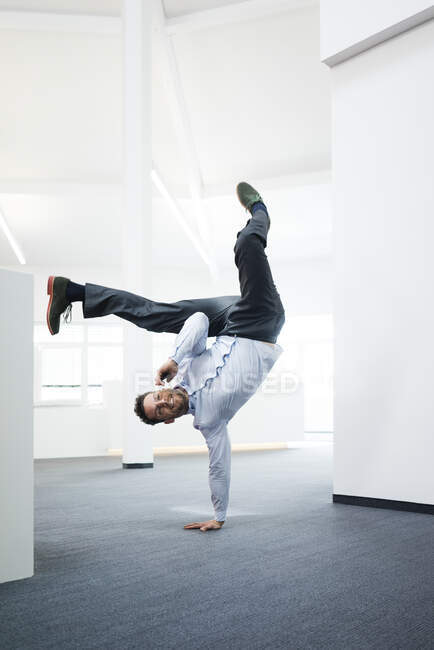 Geschäftsmann mit Handy macht Einhand-Handstand auf Büroflur — Stockfoto