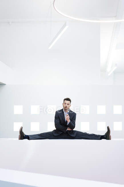 Businessman doing the splits on reception desk in office — Stock Photo