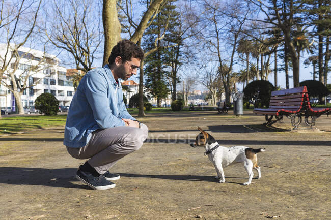 Молодий чоловік навчає собаку в парку. — стокове фото