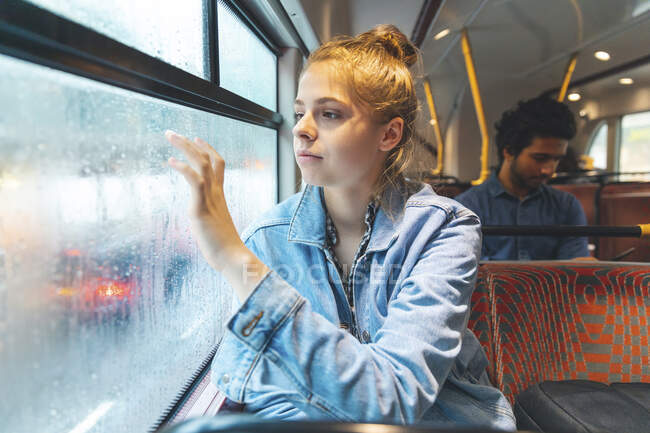 Giovane donna in autobus che scrive sul vetro della finestra appannato con il dito, Londra, Regno Unito — Foto stock