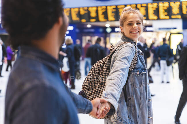 Retrato de jovem mulher feliz de mãos dadas com seu namorado na estação de trem — Fotografia de Stock