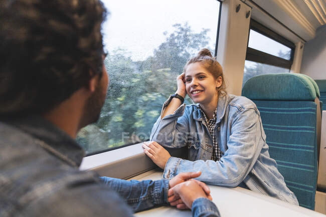 Retrato de una joven sonriente viajando en tren con su novio, Londres, Reino Unido - foto de stock