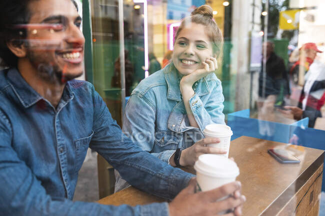 Портрет усміхненої молодої жінки в кав'ярні, що дивиться на молодого чоловіка — стокове фото