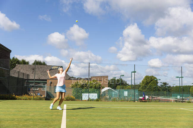 Donna matura che serve durante una partita di tennis sul campo di erba — Foto stock