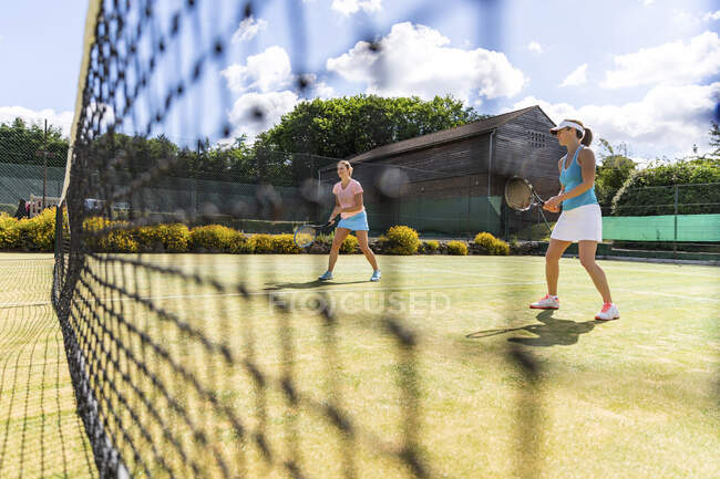 Зрелые женщины во время теннисного матча на травяном корте — стоковое фото