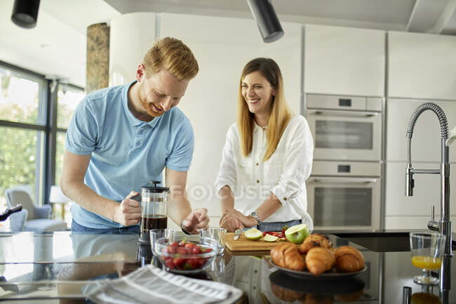 Couple standing in kitchen, preparing healthy breakfast, chopping fruits — Stock Photo
