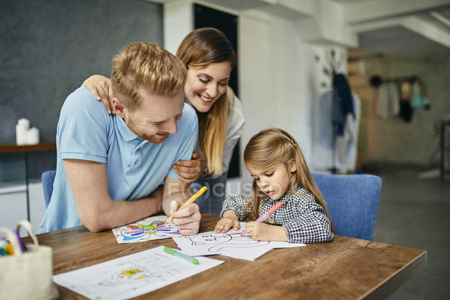 Mutter und Vater beobachten Tochter beim Malen von Malbuch — Stockfoto