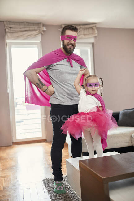 Padre e hija jugando superhéroe y supermujer - foto de stock