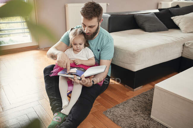 Батько з донькою читають книжку. — стокове фото