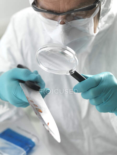 Científico forense examinando un cuchillo tomado de una escena de crimen violento en el laboratorio - foto de stock