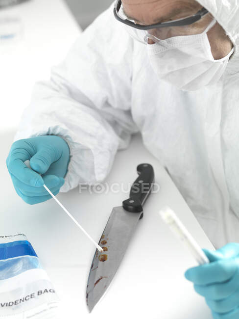 Forensic scientist taking DNA evidence from a blood smeared knife — Stock Photo