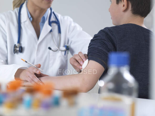 Ärztin gibt einem Jungen in der Klinik eine Routineimpfung — Stockfoto