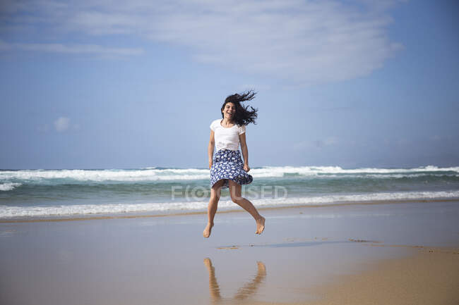 Femme riante sautant dans les airs sur la plage, Fuerteventura, Espagne — Photo de stock