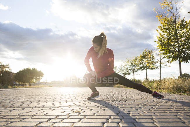 Молодая женщина растягивает ногу в парке — стоковое фото
