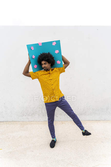 Junger Mann trägt gelbes Hemd, blaues Hinweisschild mit Pfeilzeichen — Stockfoto