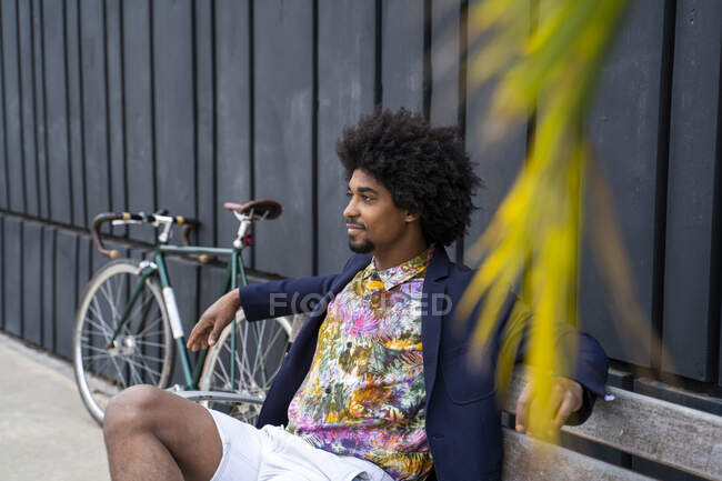 Стильный мужчина с велосипедом, сидящий на скамейке — стоковое фото