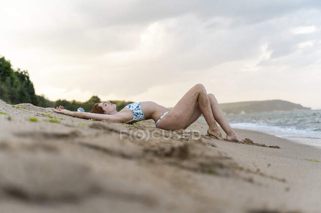 Giovane donna sdraiata sulla spiaggia — Foto stock