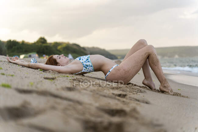 Junge Frau liegt am Strand — Stockfoto