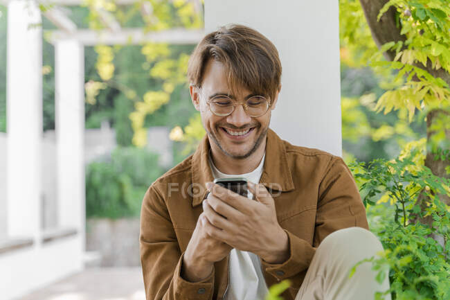 Портрет смеющегося человека, смотрящего на мобильный телефон — стоковое фото