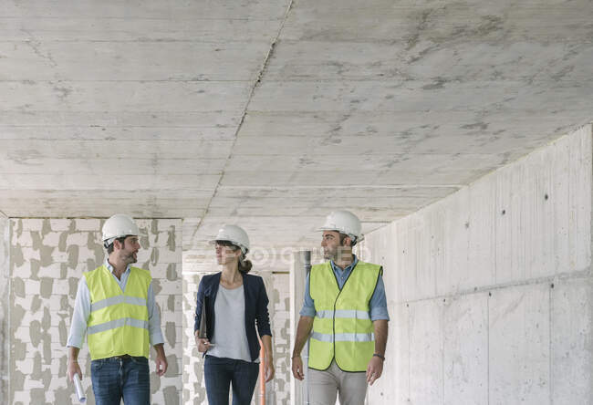 Male architects and female manager talking while walking at construction site — Stock Photo
