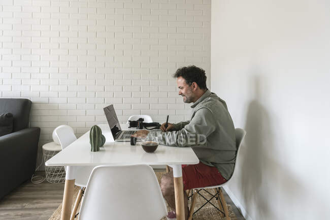 Людина сидить за столом і працює над графічним планшетом і ноутбуком. — стокове фото