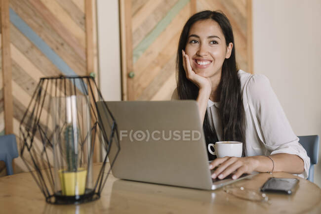 Молода бізнесменка з ноутбуком за столом у кафе після перерви. — стокове фото