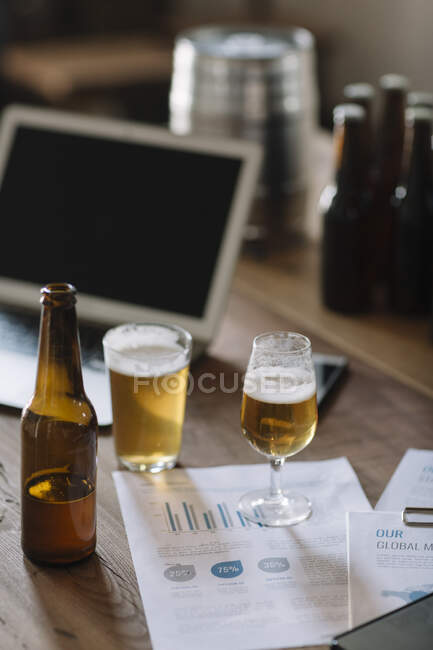 Primer plano de un vaso de cerveza con un portátil en un restaurante. - foto de stock
