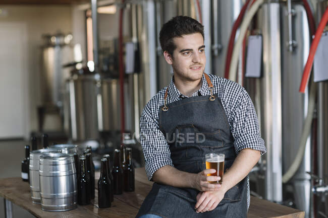 Jeune homme buvant une bière dans une brasserie — Photo de stock