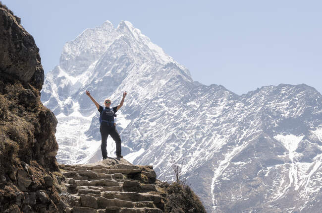 Mujer feliz levantando brazos frente a la montaña Thamersku, Himalaya, Solo Khumbu, Nepal - foto de stock