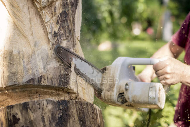 Wood carver carving sculpture, using chainsaw — Stock Photo