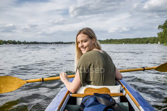 Lächelnde Frau paddelt auf einem See — Stockfoto