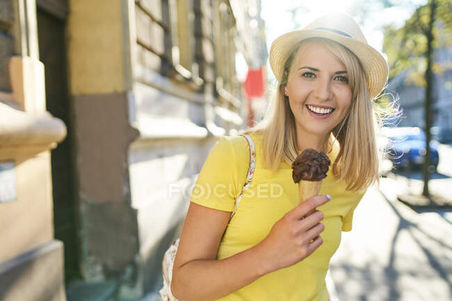 Retrato de uma jovem sorrindo desfrutando de um sorvete na cidade — Fotografia de Stock