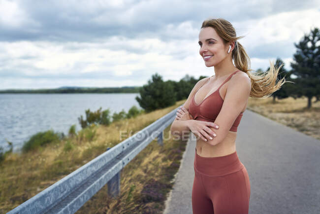 Femme athlétique debout à l'extérieur avec les bras croisés et regardant loin — Photo de stock